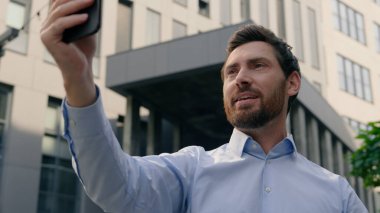 Smartphone sohbet video konferans uygulaması konuşan web kamerası beyaz iş adamı gülümseyen orta yaşlı adam iş adamı girişimci şehirdeki sanal sohbet cep telefonu çevrimiçi