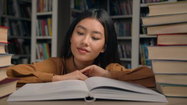 Odaklanmış Asyalı kız öğrenci etnik kitap kurdu okuyucusu üniversite kütüphanesinde kitap okuyor. Üniversite sınavına hazırlanıyor. Edebiyat okuyor.