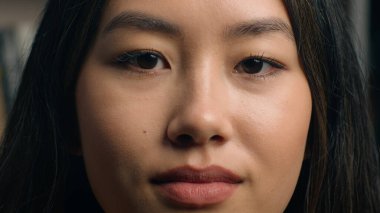 Ciddi yoğunlaşmış Asyalı kız öğrenci genç iş kadını iş kadını bayan öğretmen müşteri onaylıyor. Kapalı kitaplığın yanında duran delici sert bakışlı kameraya bakarak onaylıyorum.