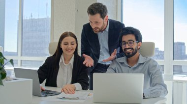 Takım lideri, çeşitli ofis çalışanlarına başarılı bir iş sözleşmesi imzalayan meslektaşlarını gösterdi. Üç çok ırklı iş adamı ve iş kadını takım çalışmasını kutladılar.