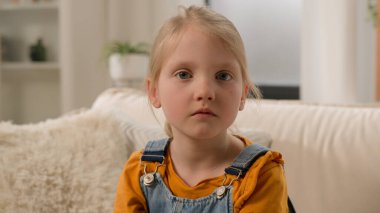 Yakın plan portre biraz kırgın üzgün üzgün üzgün ciddi endişeli Kafkasyalı anaokulu kızı kız çocuk kız çocuğu evde yalnız başına kameraya bakıyor kötü davranışın cezası hakkında üzüntü