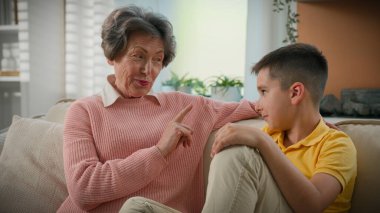 Beyaz büyükanne, şımarık torunu cezalandırmayı, işaret parmağını titretmeyi, yaşlı kadını, şefkatli anneanneanneyi, evdeki mutlu aile koltuğunda oturan torun çocuğa disiplin öğretmeyi anlatıyor.