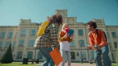 Üç mutlu çok ırklı öğrenci kız Afrikalı kadın, beyaz erkek, erkek, üniversitenin yakınındaki bir şehirde, kitap fırlatıyor. Eğitim sınavlarını başarıyla geçti.