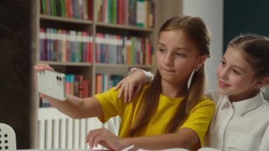 Okul eğitimi Kafkasyalı küçük kız öğrenciler liseli kızlar ders çalışıyor eğlence molası veriyorlar selfie fotoğraf makinesi bağımlısı kadın arkadaşlar çocuklar blogcular cep telefonu blogu blogu