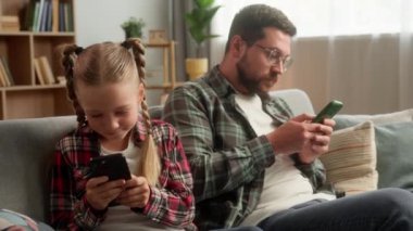 Gadget bağımlılığı. Kafkas aile çocuğu çocuk babası baba cep telefonu akıllı telefon oyunu uygulaması kullanıyor küçük çocuk babayla sohbet ediyor ev kızı internette gezinen adamı görmezden geliyor.