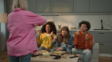 Mutlu ev partileri komik dört çok ırklı insan çok ırklı arkadaş eğleniyor beyaz kadın pandomim gösterisi yapıyor gülümseyen Afrikalı erkekler erkek kız kızlar tahmin ediyor