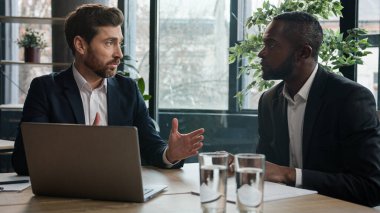 Two diverse businessmen multiracial men at office with laptop. Caucasian financial advisor manager consultant insurance agent consulting African American man client talk show business presentation