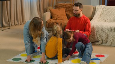 Kafkasyalı mutlu aile babaları twister oynayan çocuklar akşam evde eğleniyor hafta sonu tatilleri neşeli çocuklar kaygısız çocuklar küçük kızlar gülüyorlar anne babaları çocukluk oyun zamanı eğleniyor.