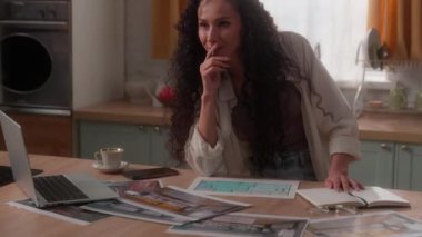 Ev yapımı dizayn şablonlarıyla evde çalışmakla meşguldüm. Düşünceli, düşünceli, iç mekan fotoğrafları seçmekle meşguldüm. İspanyol tasarımcı, bayan ev sahibi kadın.