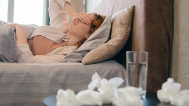 Bir bardak su ve ilaç. Hasta beyaz kız, yatak odasında acı çeken sağlıksız bir kadın. Ağrı kesici baş ağrısı.