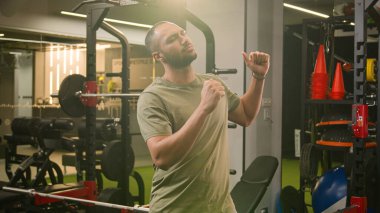 Mutlu Afrikalı Amerikalı erkek kaslı spor antrenörü spor kulübü eğitmeni Latin sporcu dans ederken eğleniyor spor aletlerinin yanındaki müzik ritmine ayak uyduruyor.