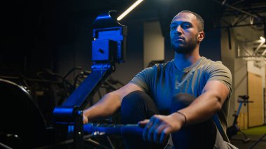 Sportif kulüp kaslarındaki ekipmanlarla spor kararlılığı sıkı egzersizi Afrikalı Amerikalı güçlü adam sporcu erkek sporcu vücut geliştirme sporcusu halat çekme kürek çekme makinesi oturma makinesi