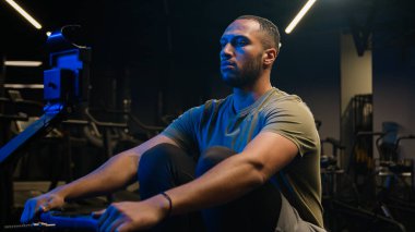 Spor antrenmanında kürek çekme makinesi simülatörüyle spor antrenmanı spor kulübü hedeflerinde alçak sırada oturmak Afro-Amerikan erkek sporcu sporcu vücut geliştirici sporcu sporcu sporcu sporcu sporcu