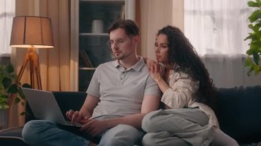 Kafkasyalı çift, erkek aile babası, erkek arkadaş İspanyol kadın, kız arkadaş, kanepe, kanepe, dizüstü bilgisayar, internet üzerinden alışveriş siparişi.