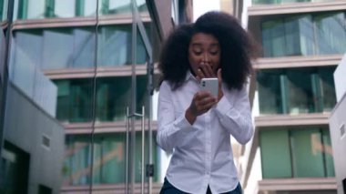 Mutlu Afrikalı Amerikalı kadın iş kadını elinde cep telefonu teknolojisi olan kadın finansman zaferi kutluyor kız iş anlaşması kazandı yönetici işveren e-ticaret şehir dışında neşe yarattı