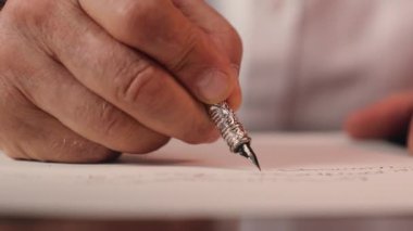 Erkeğin eli dolmakalem tutarken kapanır. Kağıt yazma sözleşmesi yazar. El yazısı imzası mektup masası evrakları.