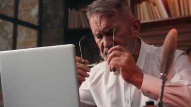 Yaşlı beyaz Avrupalı iş adamı gözlük takıyor sağlık yaşlılar dizüstü bilgisayarda çalışmaya başlıyor ev bilgisayarları finans bürosu erkek teknolojisi interneti içinde online internet.