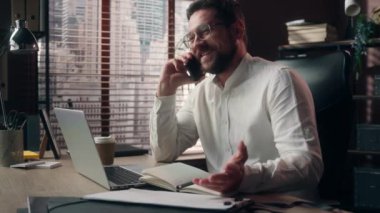 Gülümseyen Kafkasyalı, mutlu, yönetici, erkek, menajer, ofis çalışanlarıyla cep telefonu pazarlığı yapan, dokunmatik dizüstü bilgisayarlar yazan, iş planlayan, iş adamı CEO 'su.