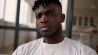 Üzgün, hayal kırıklığına uğramış etnik adam, Afrikalı, Amerikalı, ev sahibi, ev sahibi, kamera krizine bakan, ciddi, somurtkan, endişeli, sağlık sorunu depresyonu geçiren bir adam.