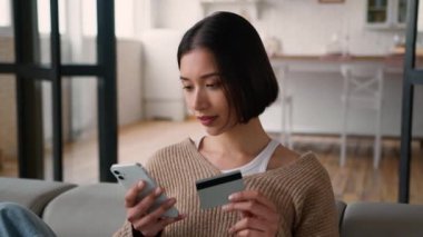 İspanyol kadın alışverişçi müşteri kız ev sahibi internetten cep telefonu kredi kartı ödemesi internet üzerinden alışveriş yapıyor. Banka uygulaması ödemeli yemek dağıtım mutfağını kullanıyor.