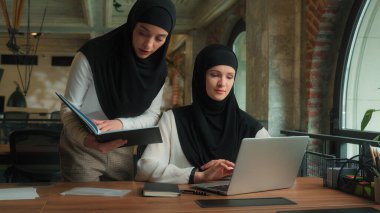 Arap Müslüman kadınlar tesettüre girmiş Arap kızlar kadın iş ortakları iş arkadaşları kadın iş kadınları çevrimiçi proje hakkında tartışıyorlar bilgisayar teknisyeni stajyer ofis laptopunda takım çalışması hakkında konuştu
