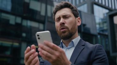 Kafkasyalı iş adamı, erkek girişimci, şehirdeki cep telefonu akıllı telefonu kullanan üzgün, hayal kırıklığına uğramış online kumar mesajı sorunu dışarıda stres kaybı yaşıyor.