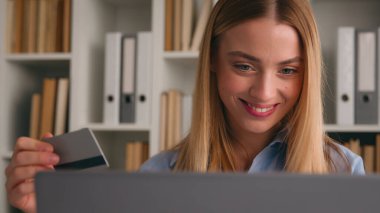 Beyaz, mutlu, gülümseyen bir kadın internet mağazasından kadın müşteri satın alan iş kadını bilgisayarla ve banka kredi kartıyla online alışveriş yapıyor. İnternet uygulamasında başarılı bir ödeme.