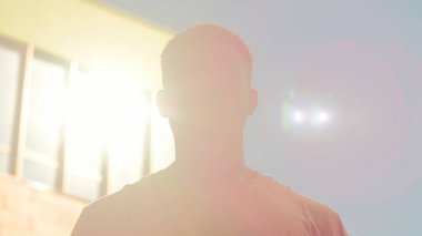 Şehirde kendine güvenen ciddi bir Afro-Amerikalı adam kameraman, erkek işadamı, işadamı, iş adamı, güneş ışınları altında turist hipster 'a bakıyor.