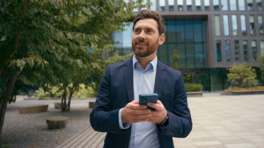 Beyaz tenli orta yaşlı pozitif işadamı, şehir erkek girişimci işadamı iş adamı sohbet ediyor, akıllı telefon ağı ile uzak iletişim bağlantısı kuruyor cep telefonuyla mesajları kaçırıyor.