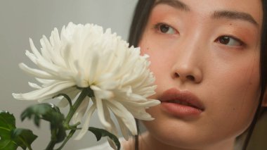 Tropik çiçekleri tutan iki şehvetli çok ırklı kız, doğal cilt kozmetolojisi ile karşı karşıya. Çok ırklı Japon Asyalı Kafkasyalı kadınlar, kozmetik, organik yumuşaklık, güzellik.