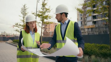İki müteahhit inşaat mühendisi elektrik bakım planı kağıt ortaklığını tartıştı takım çalışması şehir binaları inşaatları kadın mimarlar şehir gelişimini planlıyorlar