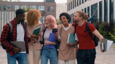 Üniversite arkadaşlığı komik duygusal neşe dolu çeşitli insanlar lise öğrencileri mutlu çok ırklı sınıf arkadaşları çok ırklı öğrenciler gülerek yürüyen şehir hakkında konuşuyorlar.