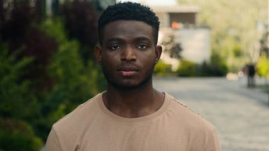 Kapalı erkek ciddi bir binyıl genç Afrikalı Afrikalı Amerikalı yakışıklı portre üzgün sakin şehir dışında güçlü bir adam dış kameraya bakarak iş adamı öğrenci vesikalık gezgini pozu veriyor.