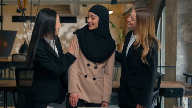 Mutlu, çok ırklı iş arkadaşları, kadın, çok ırklı iş arkadaşları, iş kadınları gülüyor, ofis portresi gülüyor, arkadaşlık birliğine sarılıyor Arap, Müslüman, Asyalı, beyaz kadınlar.