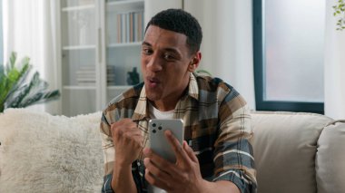 Heyecanlı afro-amerikan şok adam kazandı akıllı telefon kazandı iyi internet haberleri okudu cep telefonu başarısı karşısında şaşırdı online bahis bahsi oynayan mutlu adam evinde
