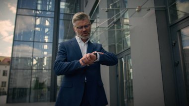Rahat orta yaşlı bir adam. Yetişkin bir iş adamı. İş adamı. Şehir dışında ofis binasının yanında yürüyor.