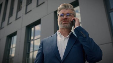 Ciddi orta yaşlı Kafkasyalı üst düzey iş adamı CEO danışman danışman çalışanı olgun erkek işadamı şehir dışında cep telefonuyla konuşan yetişkin girişimci cep telefonu konuşması