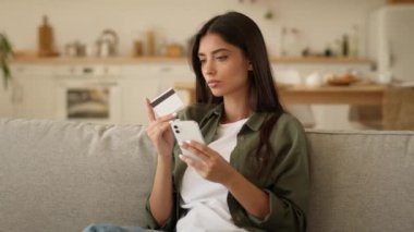 Ciddi bayan müşteri alıcısı internet üzerinden akıllı telefonuyla alışveriş yapıyor. Hintli Hintli kadın, kadın, kredi kartı ve cep telefonu satın alma siparişlerinde sorun yaşıyor.