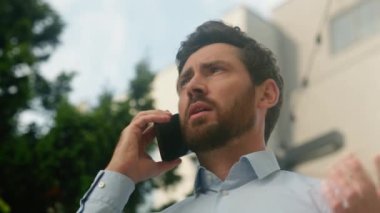 Öfkeli, sinirli, agresif, hayal kırıklığına uğramış Kafkasyalı, orta yaşlı, erkek, iş adamı, işveren, iş adamı, cep telefonuyla konuşan, tartışmalı, tartışmalı, tartışmalı, tartışmalı, tartışmalı, sorunlu, şehir güneşli gökyüzü.