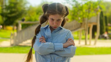 Portre üzgün küçük kız beyaz çocuk evlat edinilmiş yetim kız kaşlarını çatmış kız öğrenci kız öğrenci kızgın sağlık sorunları velayet suçu açık hava parkı şehir dışında