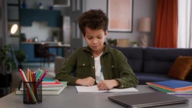 Küçük Afrikalı Amerikalı çocuk çocuk çocuk. Masadaki öğrenci. Defter defterinde yazmayı öğreniyor.