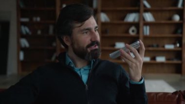 Başarılı mutlu Kafkasyalı olgun erkek CEO girişimci işadamı cep telefonu uygulaması kullanıyor sesli mesaj kaydediyor iş görüşmelerini kapalı ofis içi görüşme görüşmelerini tartışıyor.