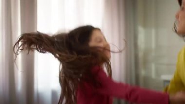 Mutlu aile ferahlığı, neşeli beyaz kadın el ele tutuşmuş küçük kız çocuk, anne ve kız müzikle dans ediyor hafta sonları evde tatilin tadını çıkarın.