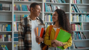Mutlu Afrikalı Amerikalı erkek İspanyol Latin kadın öğrenci kütüphane üniversite eğitimi onayını gösteriyor. Kameraya bak, gülümse, liseli kız öğrencilere gülümse.