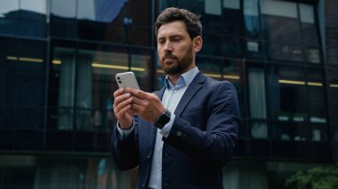 Kafkasyalı bir adam cep telefonu veri bağlantılarını araştırıyor şehir merkezindeki erkek işveren yetişkin işadamı yatırımcı adam akıllı telefon ekranı online uygulama bağımlısı açık hava