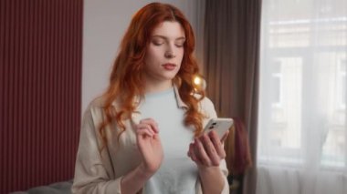 Carefree Kafkas kadın dokunmatik ekranda akıllı telefon kullanarak gevşetilmiş kadın sosyal medyada cep telefonu cihazıyla dijital görüntü kaydırabiliyor evde sakin kadın kamera siber uzay bağlantısına bakıyor