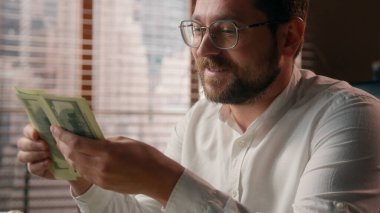 Neşeli Kafkasyalı iş adamı tüccar yönetici patron ofis çalışanlarının tasarruf hesaplarını sayıyor. Gülümseyen muhasebeci, şirket karını hesaplıyor. Nakit para kazanıyor.