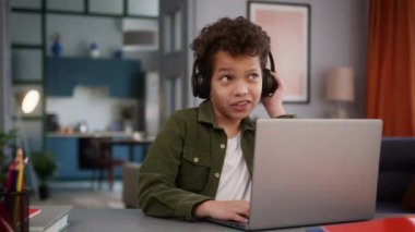 Küçük komik Afrikalı Amerikalı çocuk çocuk çocuk çocuk oyuncağı oyuncağı oyun çevrimiçi sohbet oyunu kulaklık takıp video dinleyerek evde internet tarayıcılığı öğreniyor.