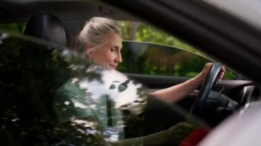 Mutlu gülümseyen Kafkasyalı olgun kadın kiralama servisi müşterisi araba camlarını açan araba sürücüsü araç kiralama aracının içindeki kameraya bakıyor.