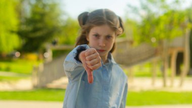 Kafkasyalı kız çocuk çocuk çocuk... ciddi üzgün, tatminsiz liseli kız öğrenci... açık hava parkı öğrencisi... baş parmak hareketi yapıyor... olumsuz zorbalık probleminden hoşlanmadığını göstermiyor.
